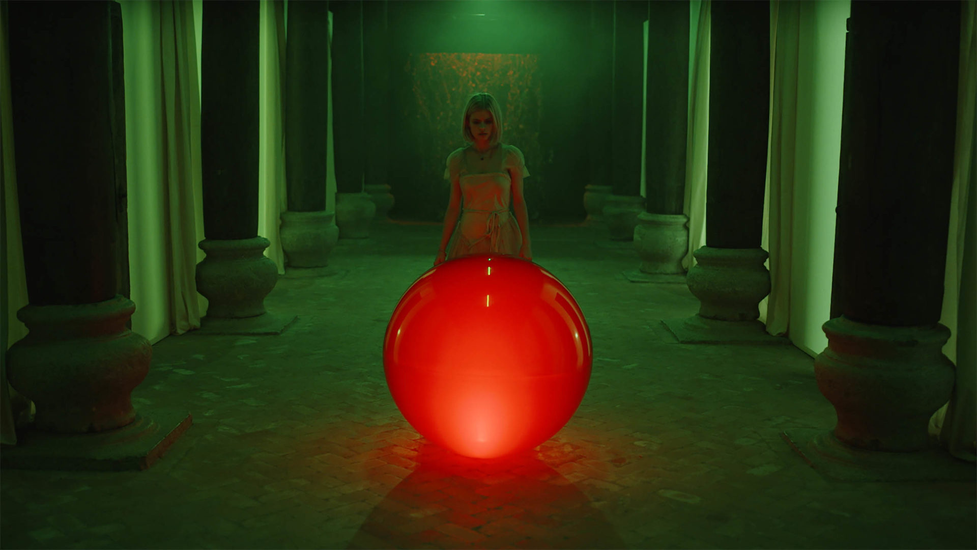 zdjęcie: kula oświetlona na czerwono za którą stoi kobieta w oświetlonym na zielono pomieszczeniu