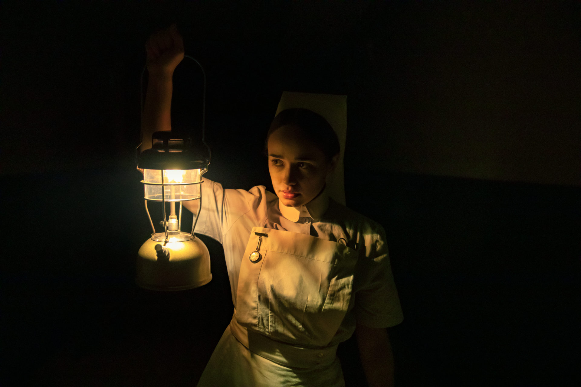zdjęcie: kobieta w starym stroju pielęgniarki z uniesioną lampą w ręce